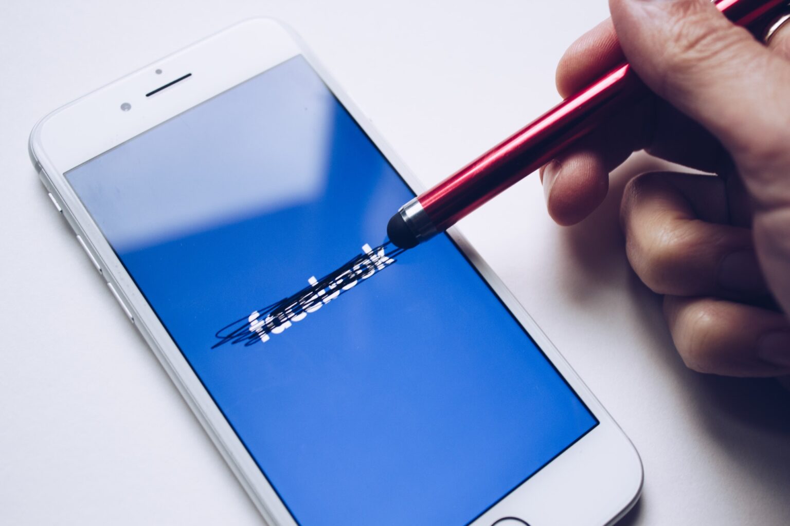 crossing out the Facebook logo on a phone with a stylus